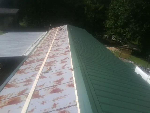 Old rusted panels beside newly installed green metal roofing — Wind Damage Roof Repair by Roofing Brothers in Wayne