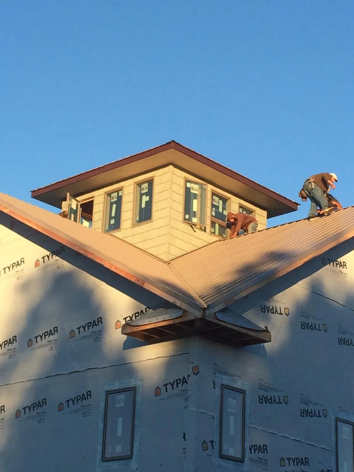 Roofers working around a rooftop cupola on a new metal roof at sunset — Roof Waterproofing in Wayne by Roofing Brothers